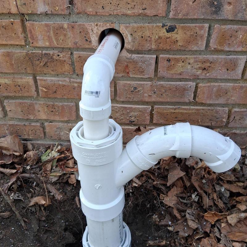 PVC sump pump discharge pipe installation outside brick wall