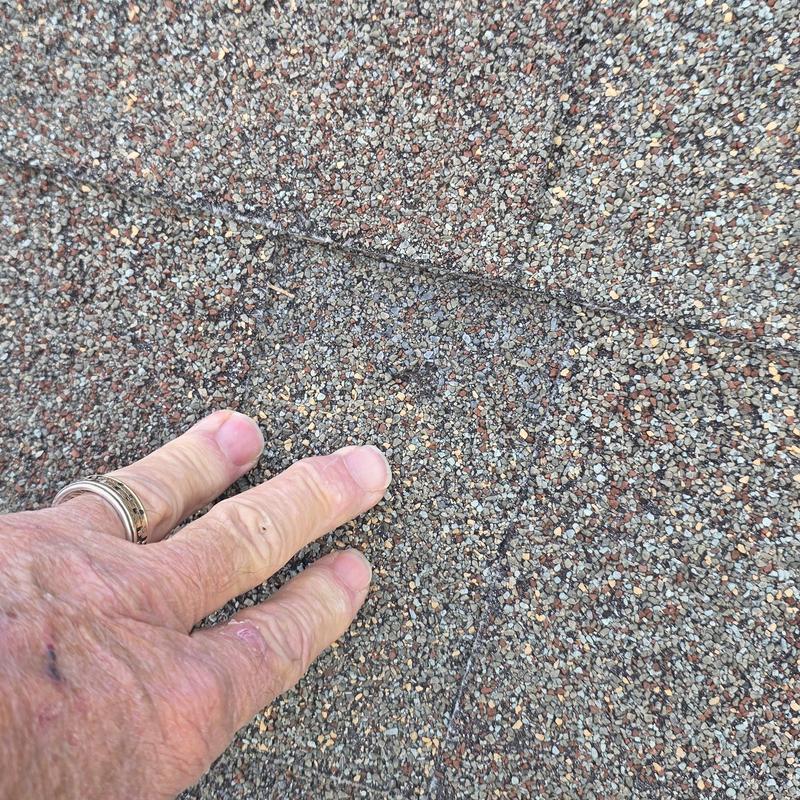 Asphalt roof shingles with hand inspecting overlap gap Asphalt roof shingles with hand inspecting overlap gap