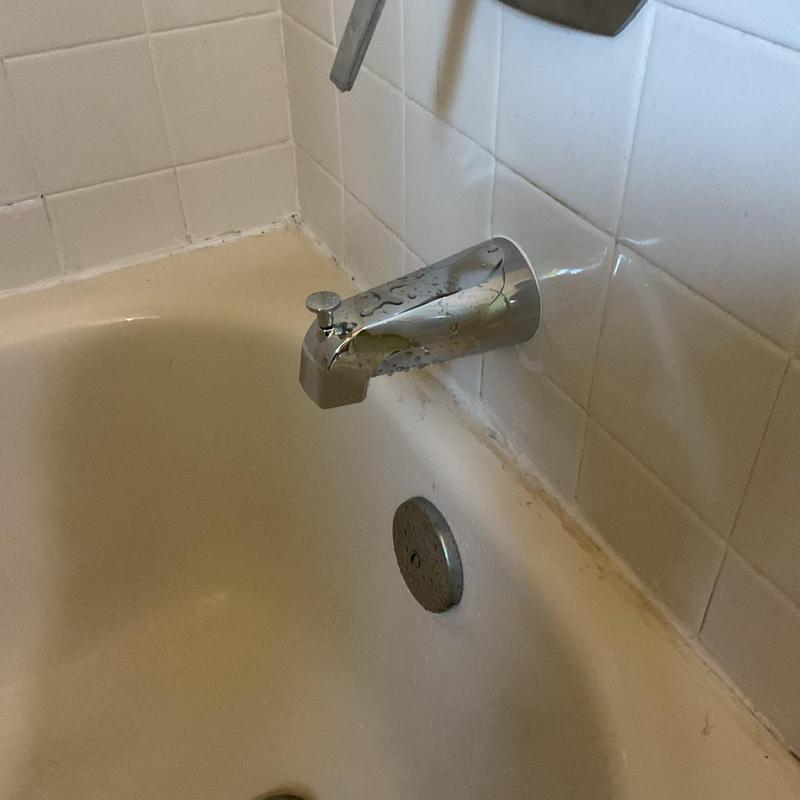 Bathtub diverter spout with water droplets on tub edge