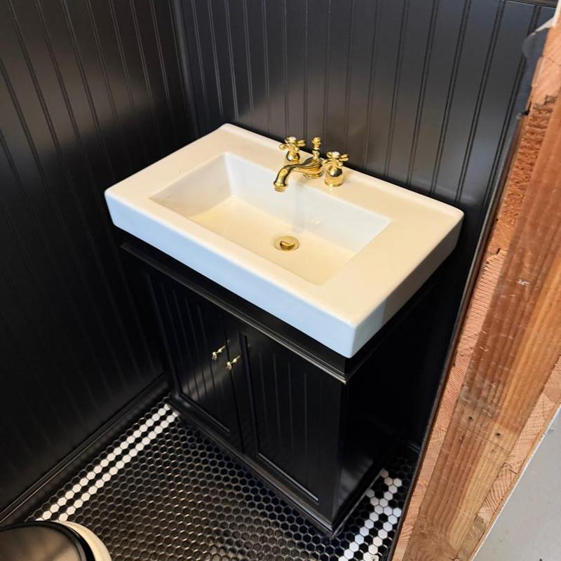 Lavatory sink with gold faucet on black vanity cabinet