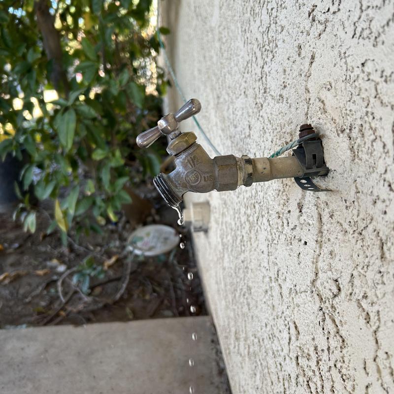 Hose bib faucet dripping water on exterior wall
