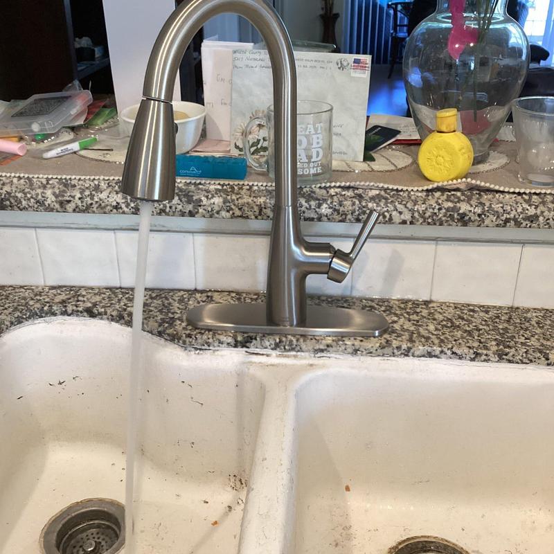 Kitchen sink faucet with water running on countertop