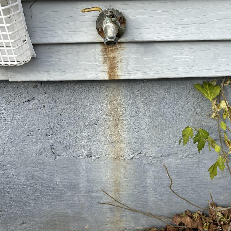 Outside frost-free faucet with rust stain on wall