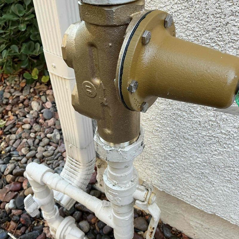 Pressure regulator double check valve on exterior wall