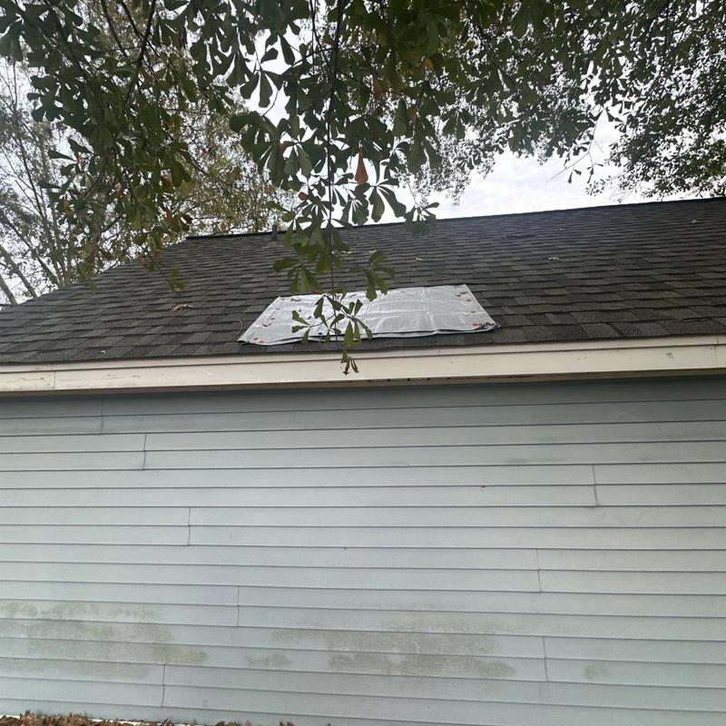 Roof shingles with temporary tarp covering damage