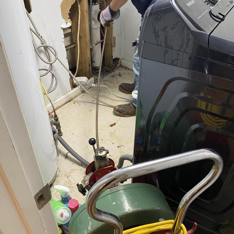 Sewer drain cable machine clearing laundry area pipe