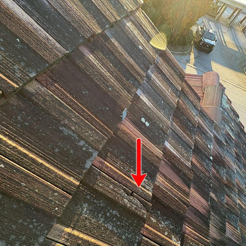 Clay roof tile with visible storm damage and crack