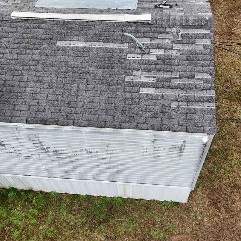 Asphalt shingle roof with damaged patches and vent pipe
