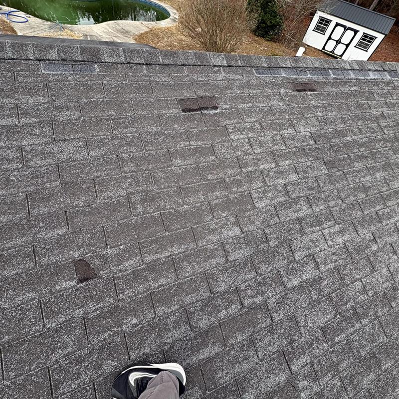 Asphalt roof shingles with visible wind damage