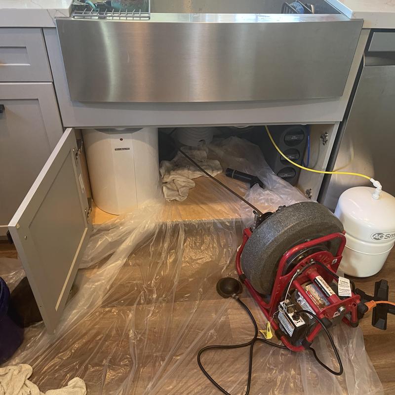 Kitchen sink drain with drain snake machine under cabinet