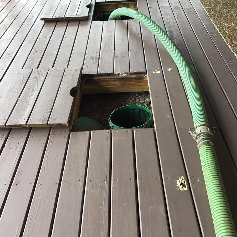 Septic tank riser with green pump hose on deck