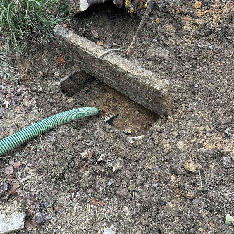 Septic tank with green pumping hose and open lid