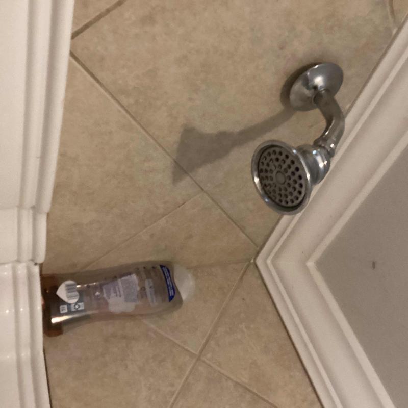 Shower head and tile floor in bathroom corner