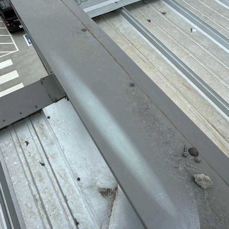 Metal roof flashing with loose screws and debris