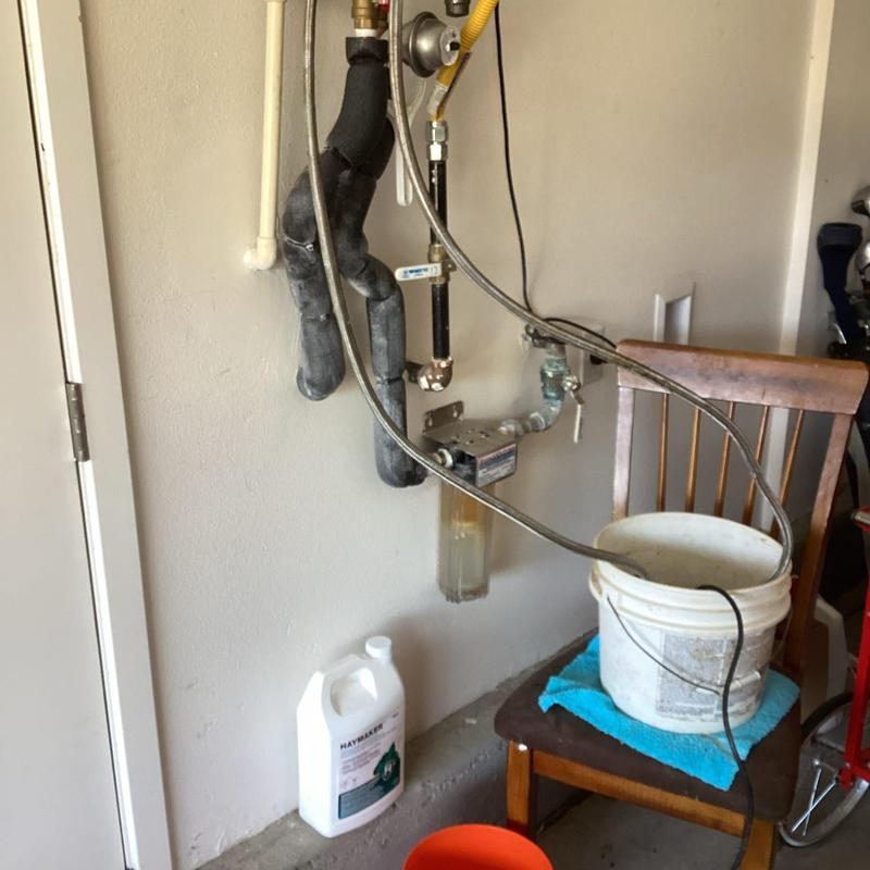 Tankless water heater flush setup with bucket and cleaning solution