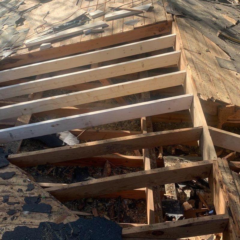 Roof rafters with new wood framing and damaged shingles Roof rafters with new wood framing and damaged shingles