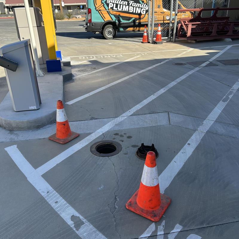 Drain cleanout with traffic cones in parking lot