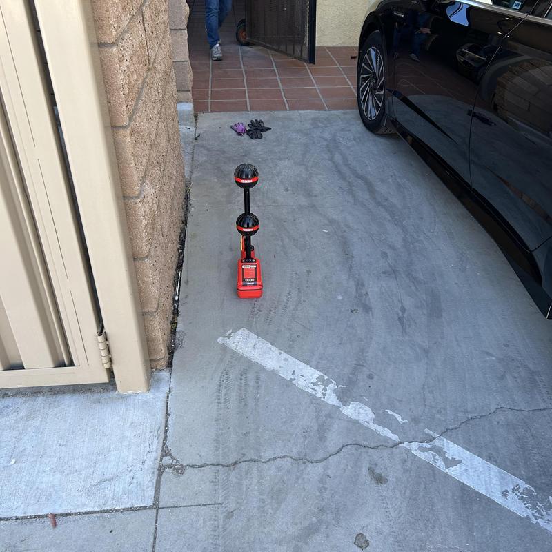 Sewer cleanout inspection tool on driveway near wall