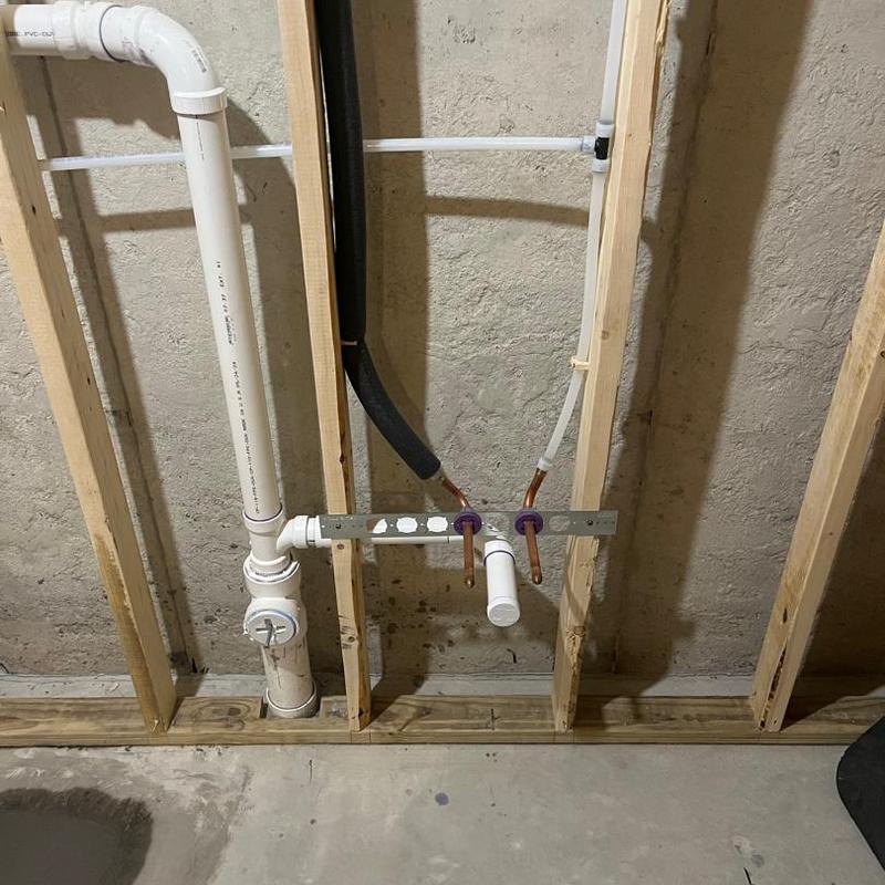 Basement plumbing rough-in with PVC and copper pipes