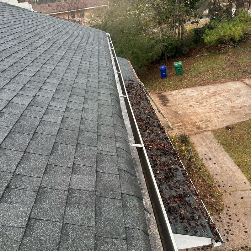 Roof gutters clogged with wet leaves and debris Roof gutters clogged with wet leaves and debris