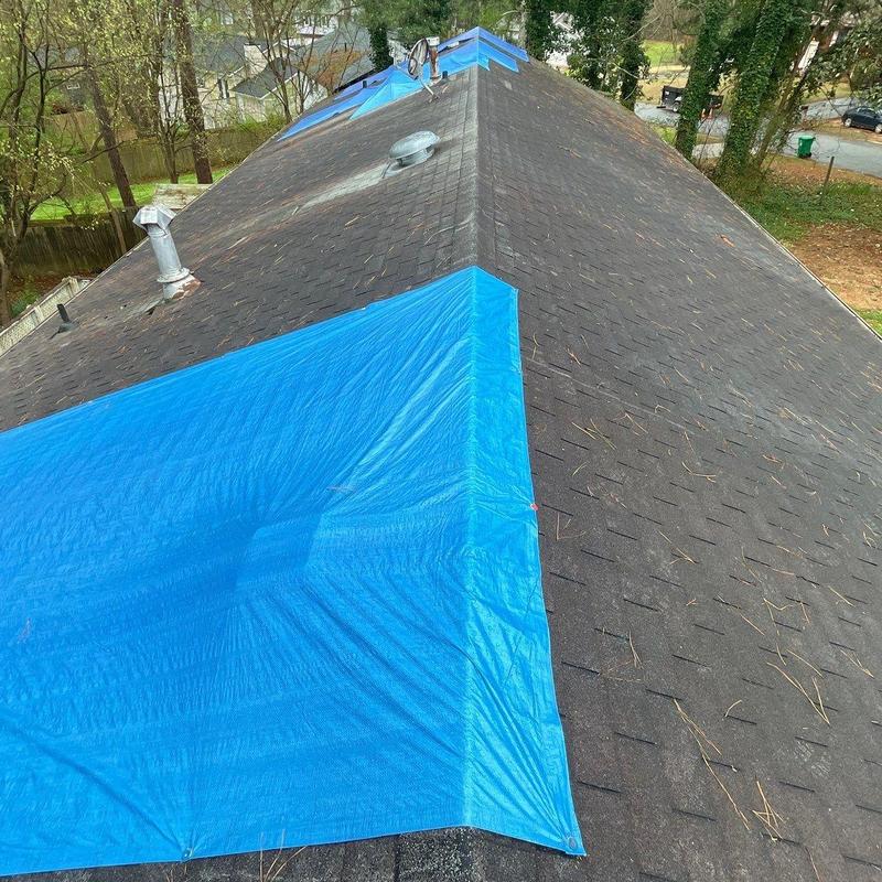 Roof shingles with blue tarp covering storm damage Roof shingles with blue tarp covering storm damage