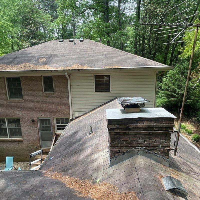 Asphalt shingle roof with brick chimney and debris buildup Asphalt shingle roof with brick chimney and debris buildup