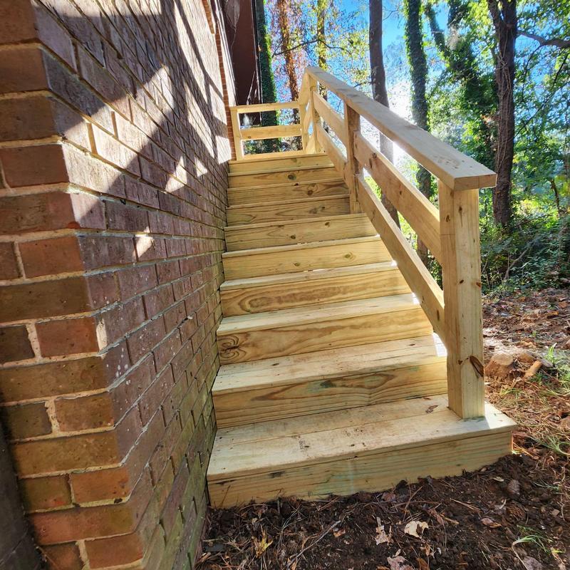 Wooden exterior deck stairs with railing beside brick wall Wooden exterior deck stairs with railing beside brick wall