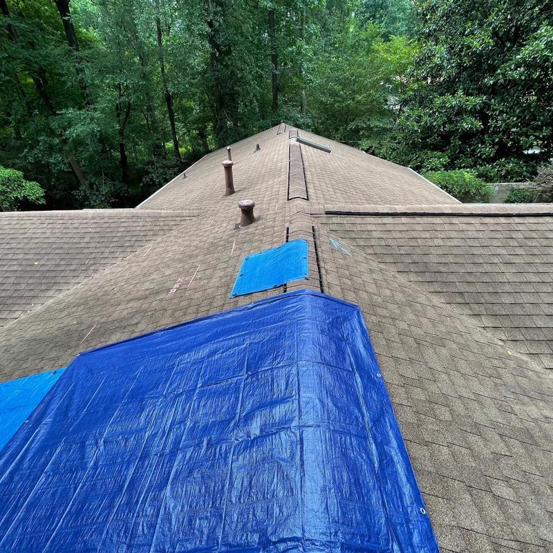 Roof shingles covered with blue tarp for protection Roof shingles covered with blue tarp for protection