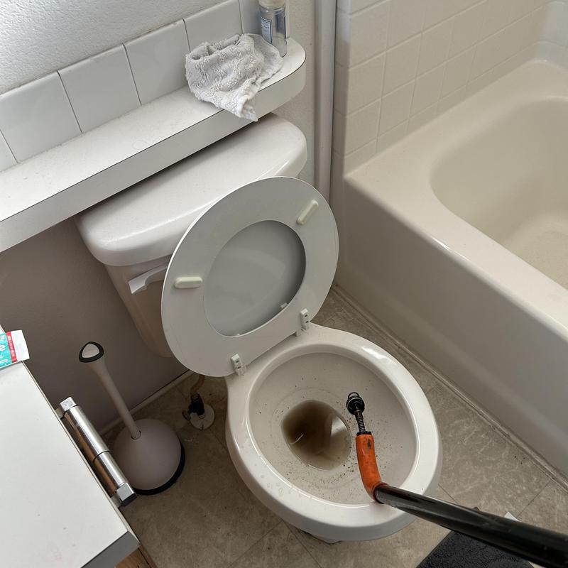 Toilet clogged with obstruction and plumbing snake inserted