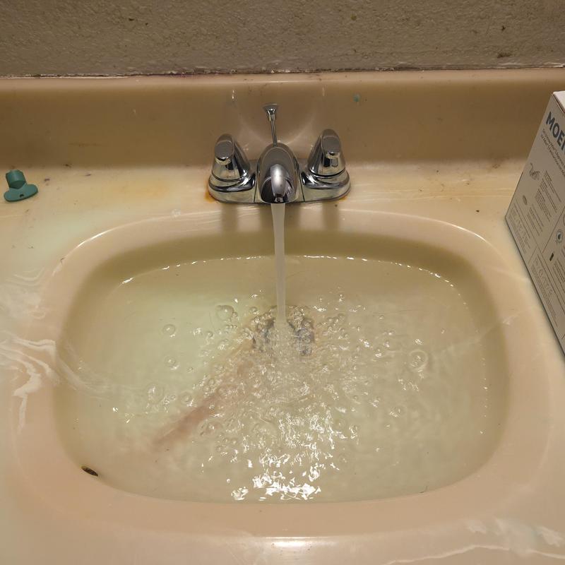 Bathroom faucet with running water and sink basin