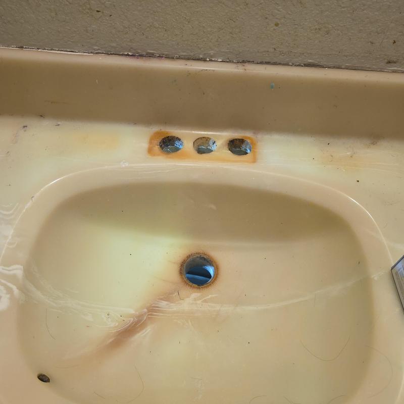 Bathroom sink with rust and stained faucet holes