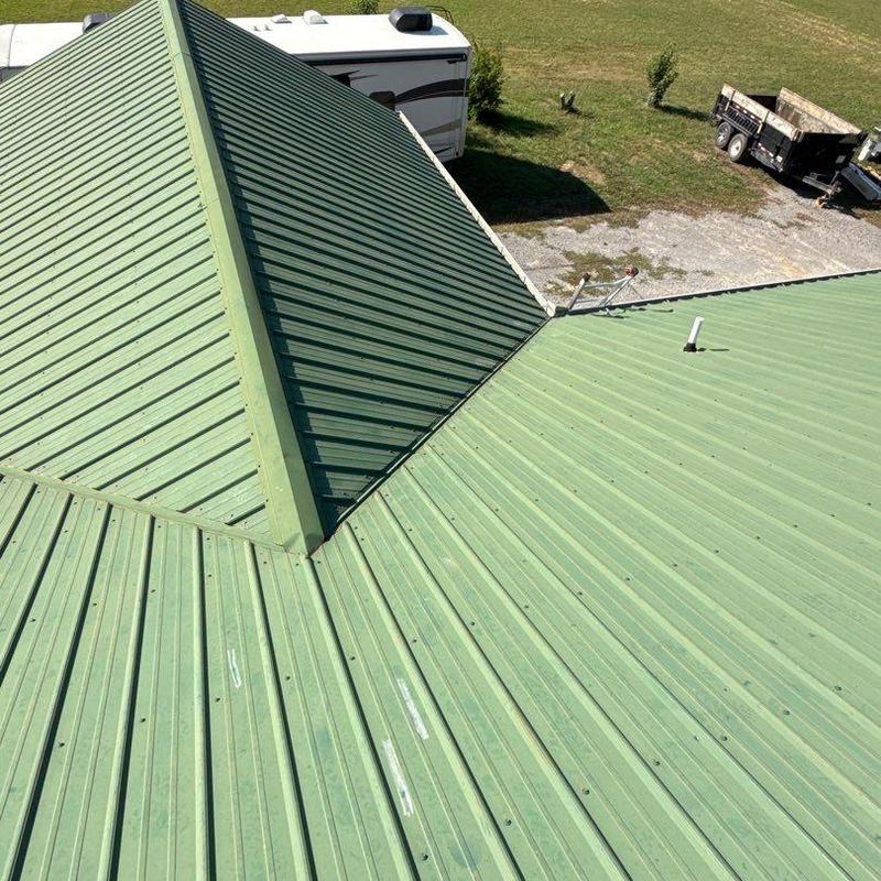 Green metal roof panels with ridge cap and vents