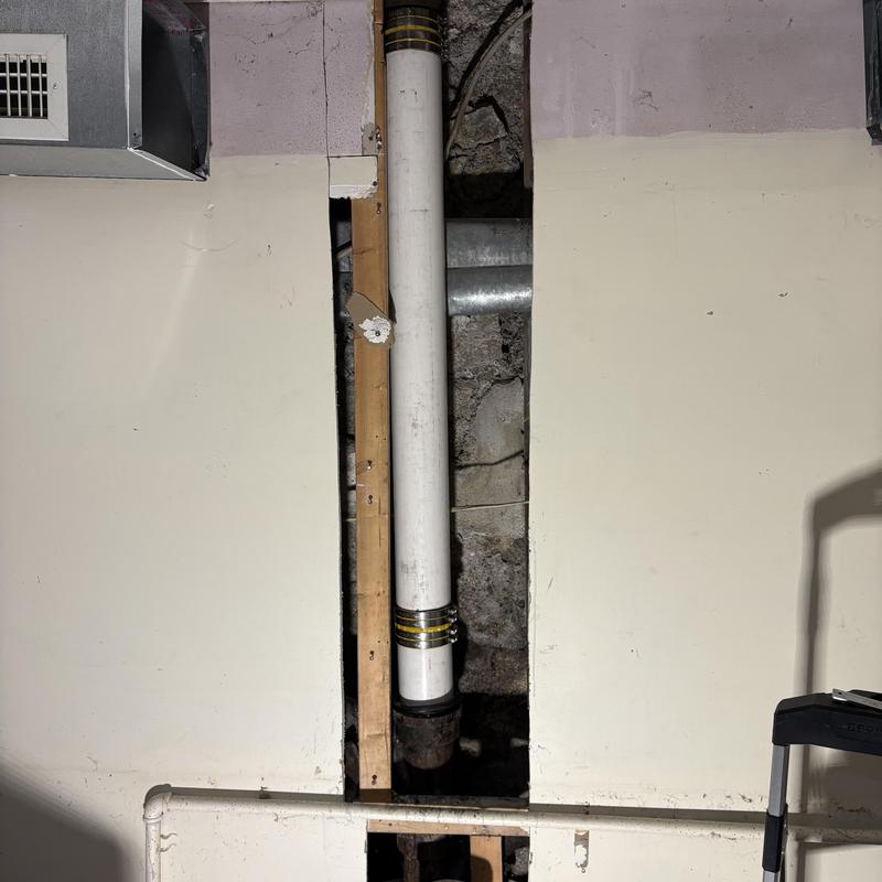 4-inch waste stack pipe with PVC repair in basement wall