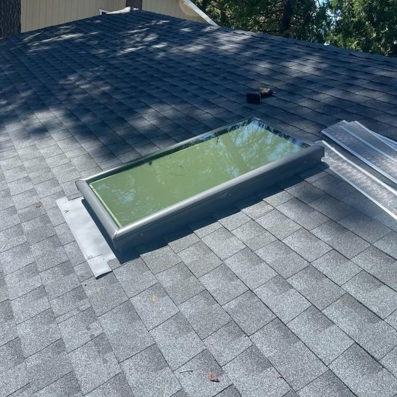 Skylight installation on gray asphalt shingle roof