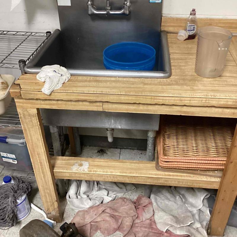 Floor drain near utility sink with cleaning supplies