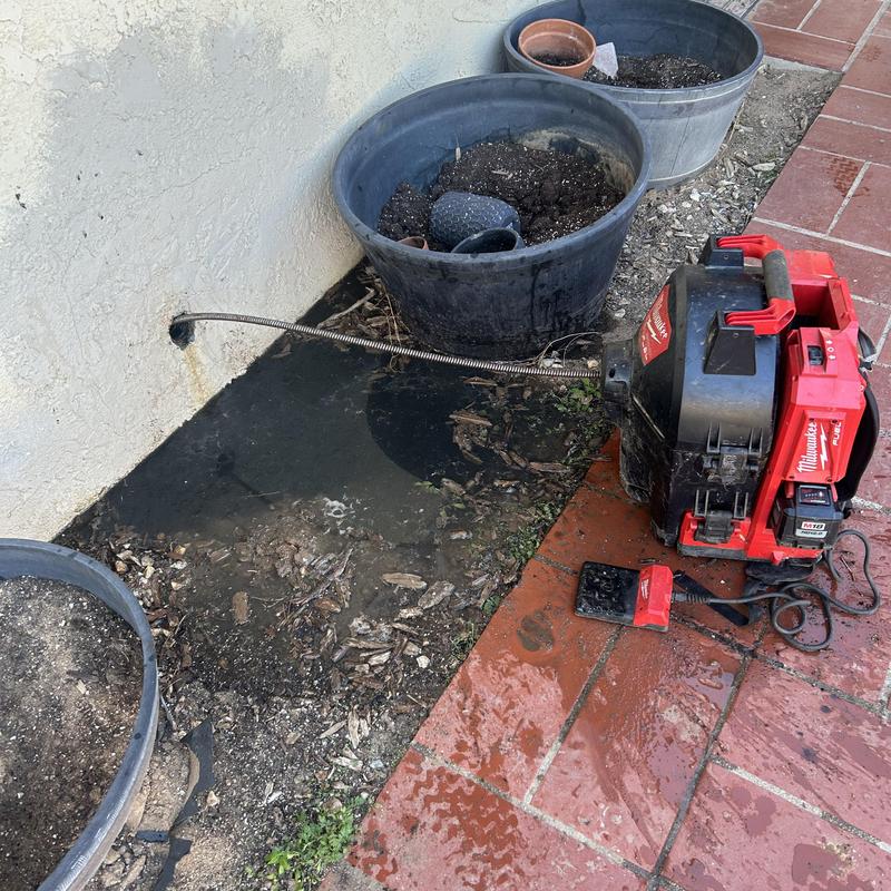 Sewer drain cleaning machine with cable in use outdoors