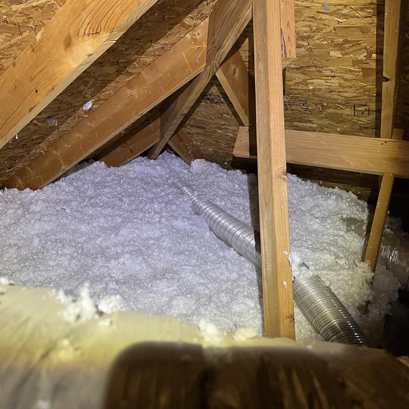 Attic insulation with metal vent duct in wood framing