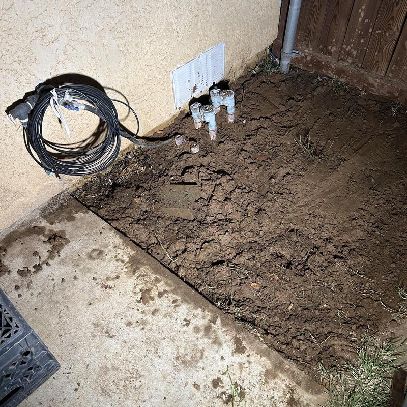 Broken PVC water main pipe exposed in yard excavation