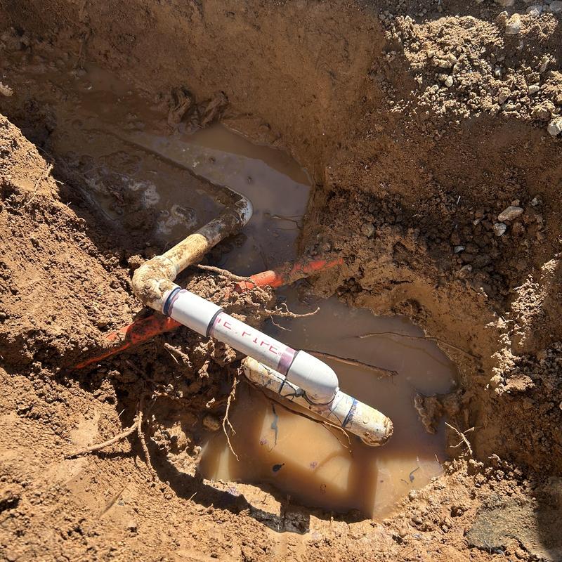 Water main with new pipe and fittings in muddy trench