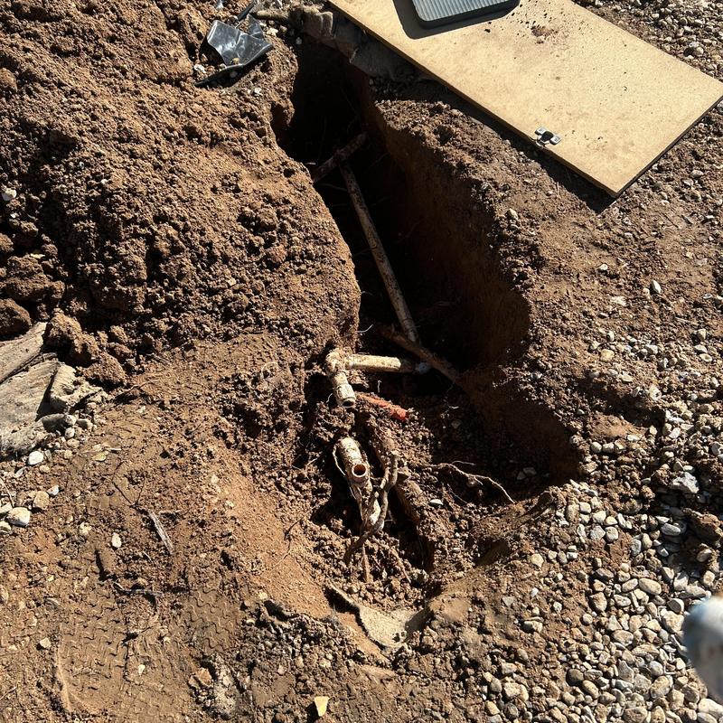 Broken water main with exposed piping in trench