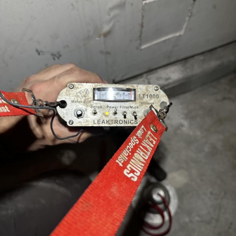 Leak detection meter held near concrete slab leak site