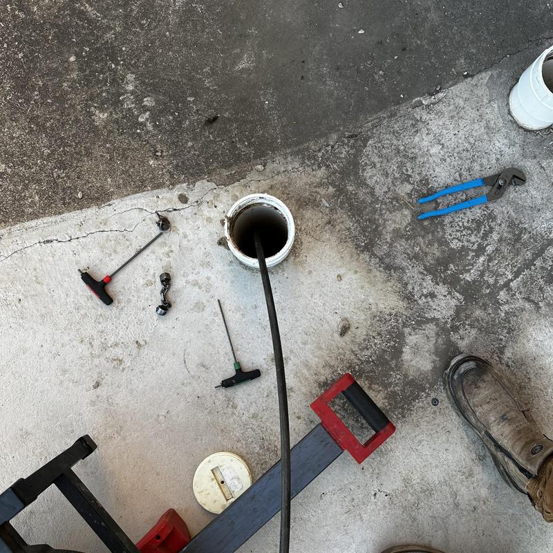 Commercial drain with plumbing snake and tools on concrete