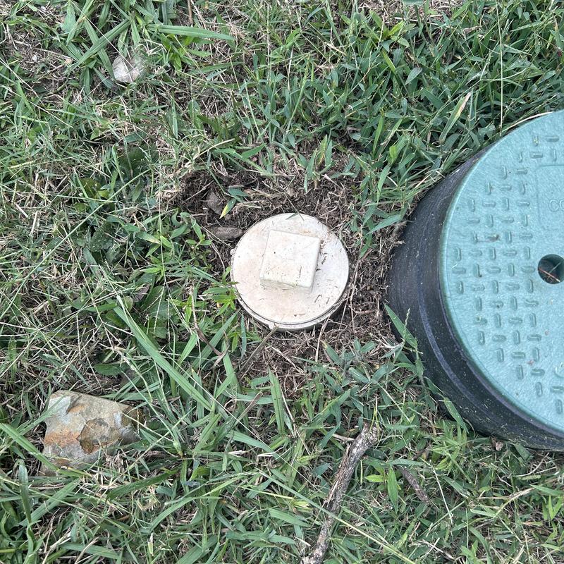 Mainline sewer cleanout and green valve box in grass