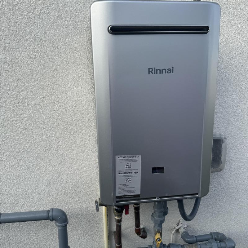 Tankless water heater with plumbing connections on wall