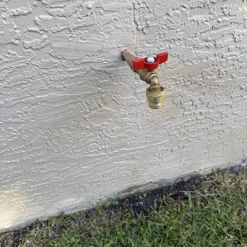12 hose bib with red valve installed on stucco wall