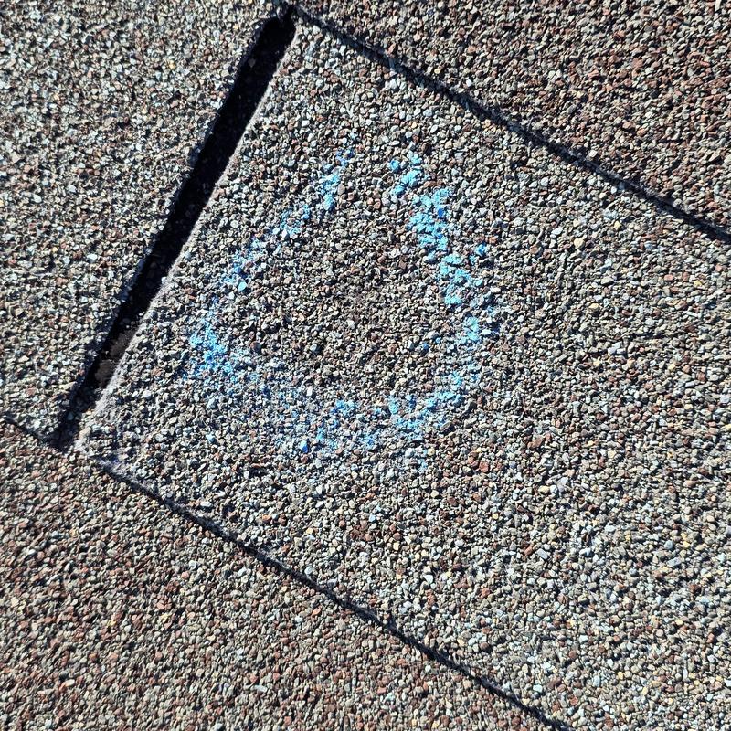 Roof shingle with blue chalk markings for storm damage inspection