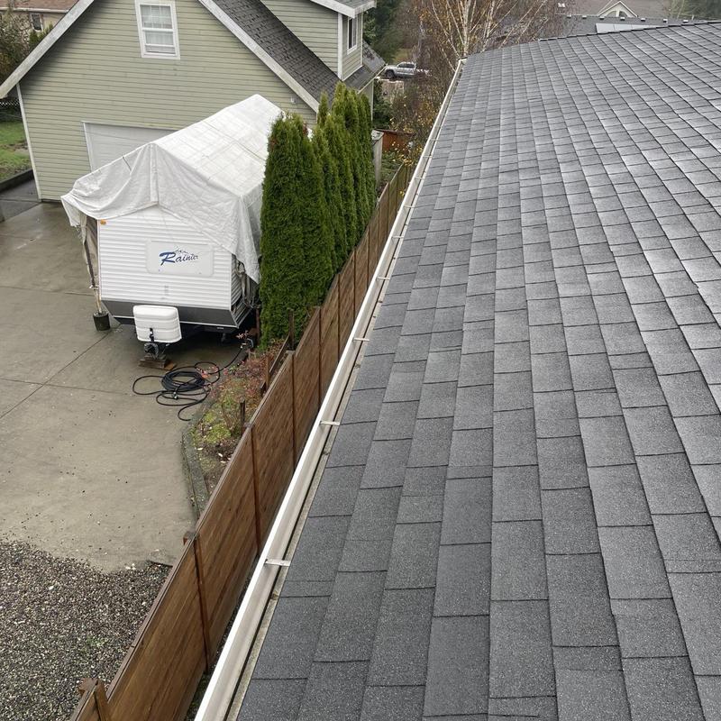 Gutter cleaning and leaf blowing on gray shingle roof