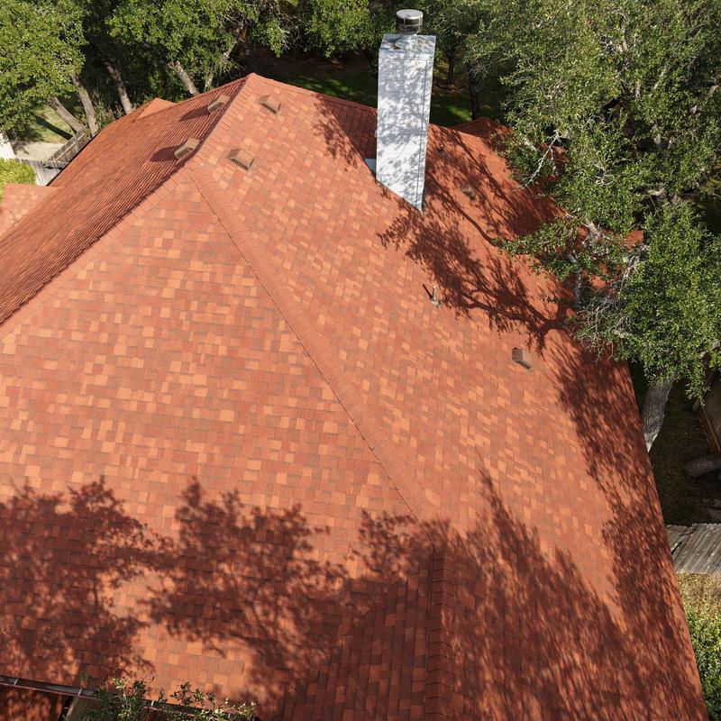 Terra cotta asphalt shingle roof with chimney in Bee Cave