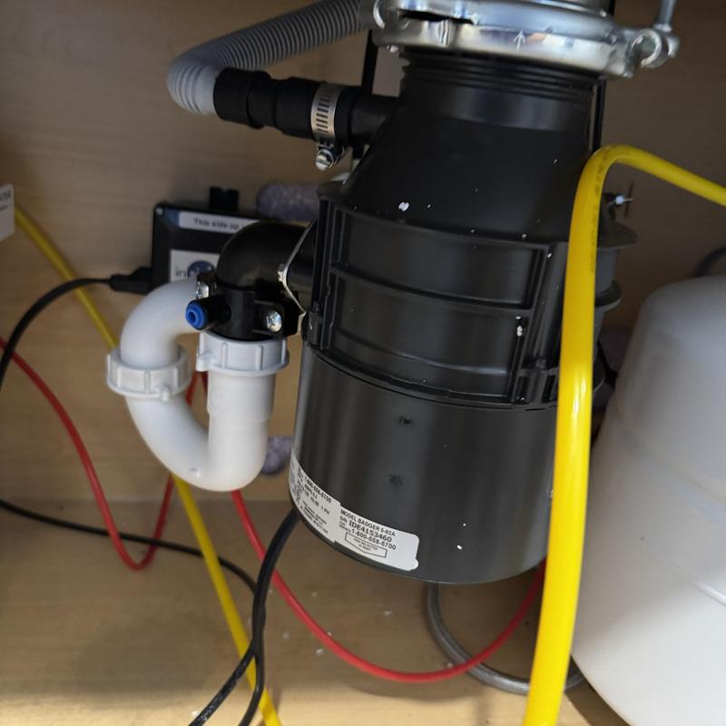 Garbage disposal unit with connected plumbing under sink