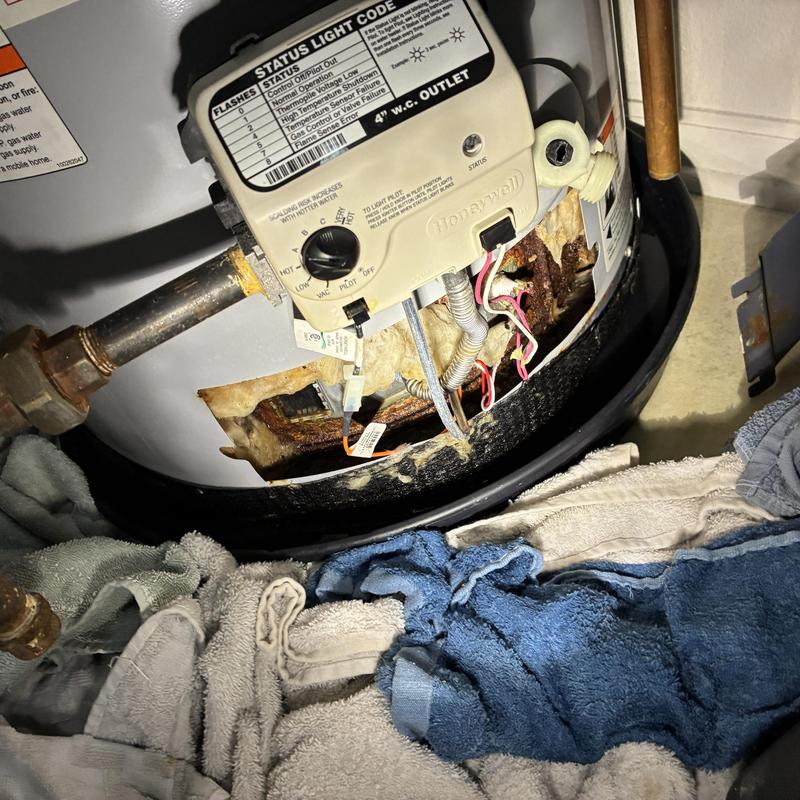 Water heater control panel and corroded base with towels